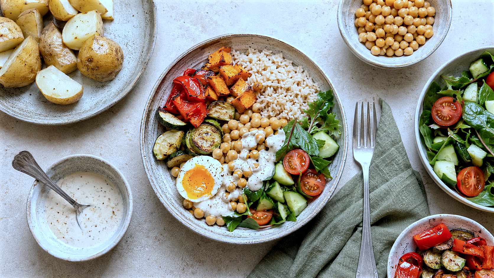 Healthy meal bowl with brown rice, chickpeas, egg, roasted vegetables and fresh salad.