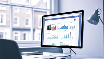 A hyper-realistic, professional photograph showing a sleek, modern home office desk in the UK. On a large, crisp monitor, a website is displayed with a vibrant, colourful SEO toolbar overlay showing data graphs and metrics. The background is softly blurred, showing a window with a typical British street scene. The lighting is bright and natural, creating a mood of productivity, clarity, and digital expertise.