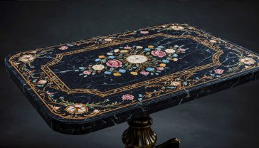 A hyper-realistic, professional photograph in the style of a museum catalogue. The shot features a beautiful antique Victorian tabletop made of polished Ashford Black Marble, its surface gleaming under soft, directional gallery lighting. The black marble is inlaid with an intricate and colourful pietra dura design of English roses and forget-me-nots, using Derbyshire minerals. The composition is a detailed close-up, focusing on the craftsmanship of the inlay. The background is a dark, subtly textured wall, creating a moody, scholarly atmosphere that evokes British heritage and craftsmanship.