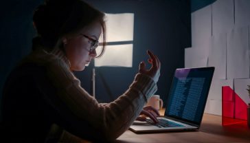 A hyper-realistic, professional photograph in the style of a modern tech publication. The image shows a frustrated-looking person in a stylish, minimalist home office in the UK, staring at a laptop screen. The screen displays a nonsensical, repetitive block of text, visually representing keyword stuffing. The lighting is clean and bright, with a shallow depth of field focusing on the laptop screen. The mood is one of confusion and overload, perfectly capturing the user experience of encountering a keyword-stuffed webpage. The colour palette is muted with a pop of colour from a plant or a mug on the desk.