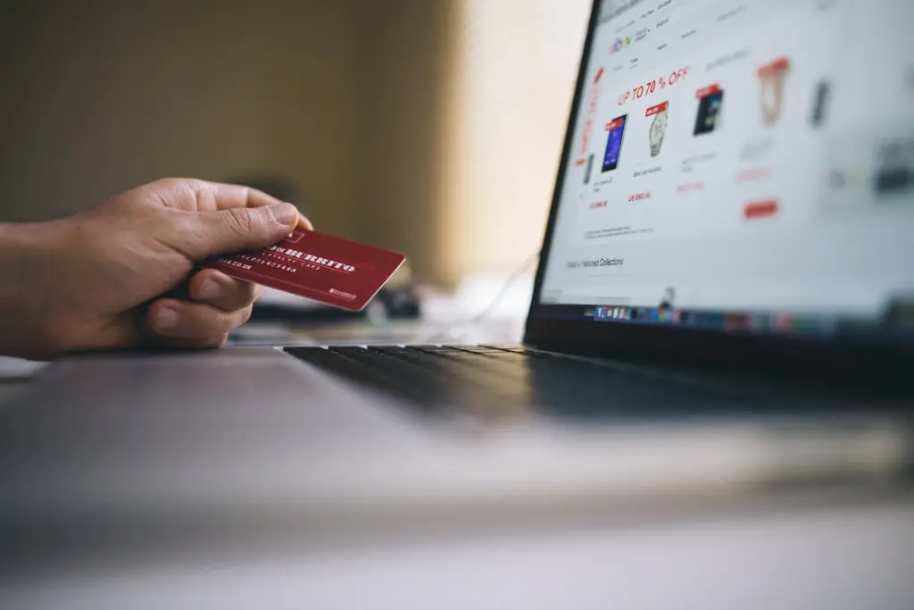 Online Shopping | A customer holds out credit card to read number as they browse eBay and visit the checkout for the first time.