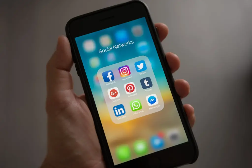 Social Media | Man holding iPhone with screen showing popular social media app icons