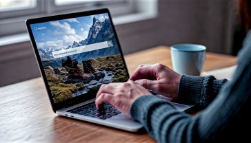 A hyper-realistic, professional photograph with a clean, modern aesthetic. The image shows a person's hands typing on a sleek laptop keyboard. On the laptop screen, a search engine interface is visible, with the search query "best waterproof walking boots for the Peak District" clearly typed in the search bar. The background is slightly blurred but suggests a cosy, contemporary home office or study in the UK, perhaps with a cup of tea and a notebook nearby. The lighting is soft and natural, coming from a window, creating a focused and productive mood. The overall colour palette is calm and professional, with muted tones.