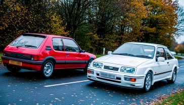 A hyper-realistic photograph in the style of a classic 1980s car magazine cover. The scene features a guards red Peugeot 205 GTI 1.9 and a diamond white Ford Sierra RS Cosworth parked side-by-side on a damp, leafy British B-road in autumn. The lighting is soft and slightly diffused, typical of an overcast UK day, making the car colours pop. The composition is a dynamic three-quarter view, with the Sierra slightly in the foreground. The mood is nostalgic, evocative of 80s performance and raw driving pleasure.