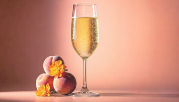 Professional product photography of a chilled glass of light gold Moscato wine with tiny bubbles, set against a soft-focus neutral background with gentle natural lighting. The glass has condensation droplets and is accompanied by fresh white peaches and orange blossoms. Shallow depth of field, crystal clear wine glass, ultra-detailed, 85mm lens, f/2.8, soft natural window lighting, professional food photography, magazine quality, advertisement style
